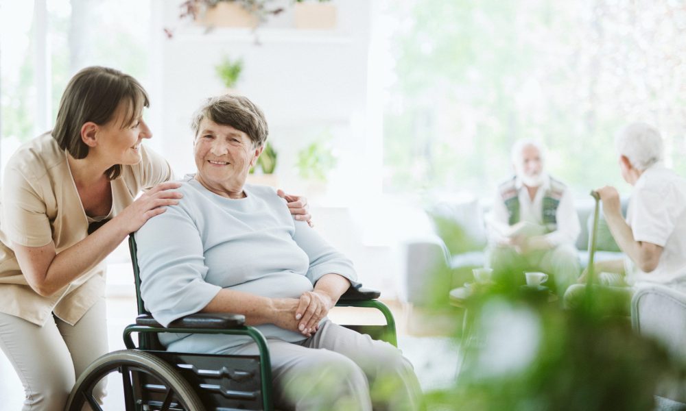 Happy caregiver with elder patient on the wheelchair