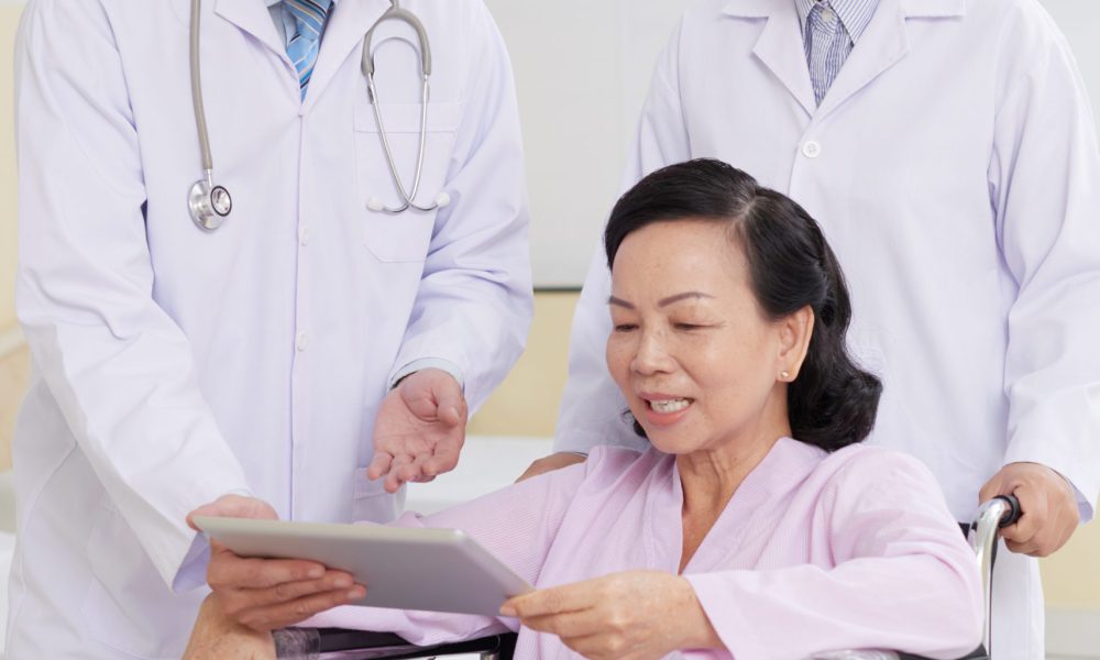 Cheerful aged woman reading doctors presctiption on digital tablet